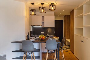 A modern kitchen with a central island, two bar stools, and pendant lighting.