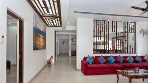 Amplia sala de estar con un sofá rojo, una mesa de centro de cristal y un adorno de pared decorativo.