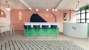 Un área de bar moderna con mostrador, taburetes y luminarias colgantes.