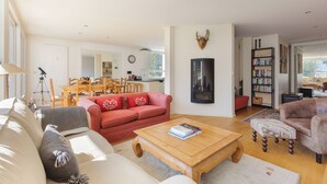 A spacious living room with a red sofa, a wooden coffee table, and a bookshelf. - Résidence La Vallée Blanche in Chamonix Balcony & Mont Blanc Views, Chamonix, France (Chamonix)