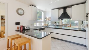 A modern kitchen with white cabinets, a black countertop, and wooden stools. - Résidence La Vallée Blanche in Chamonix Balcony & Mont Blanc Views, Chamonix, France (Chamonix)