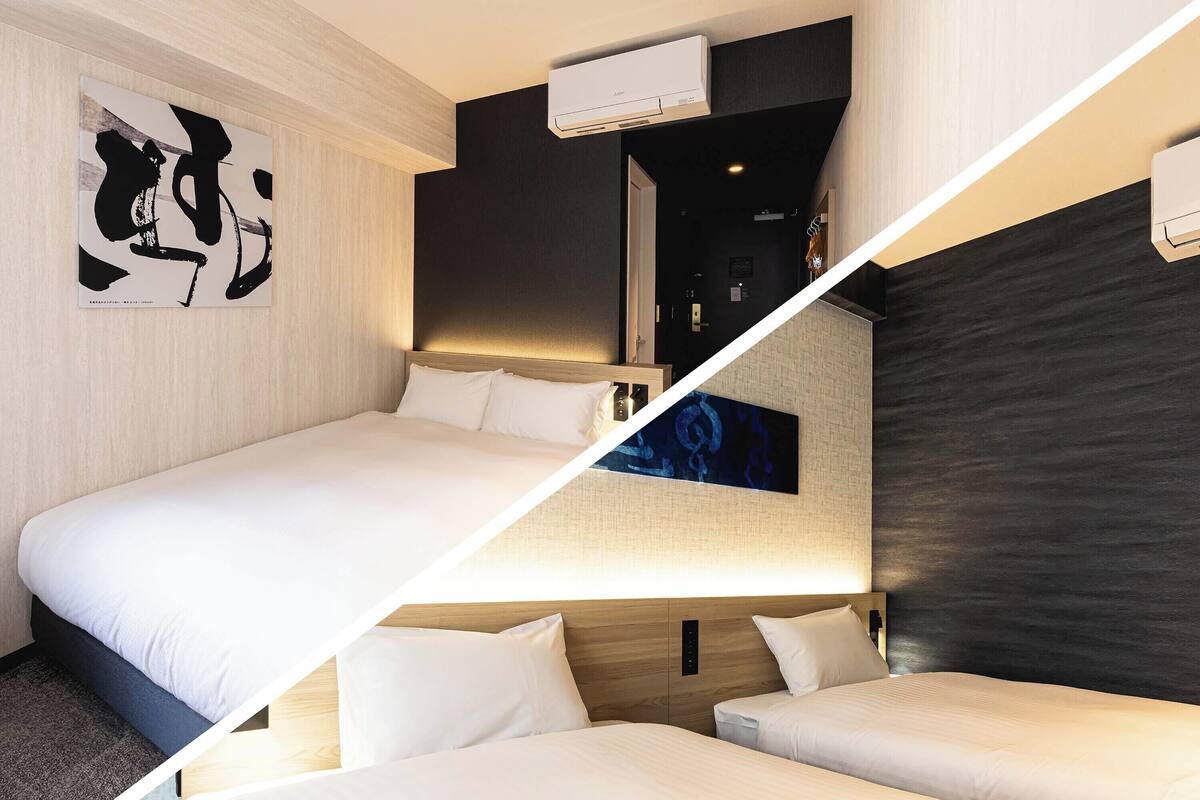 Habitación de hotel moderna con una cama grande, dos camas individuales, aire acondicionado montado en la pared y un cuadro abstracto de gran tamaño.