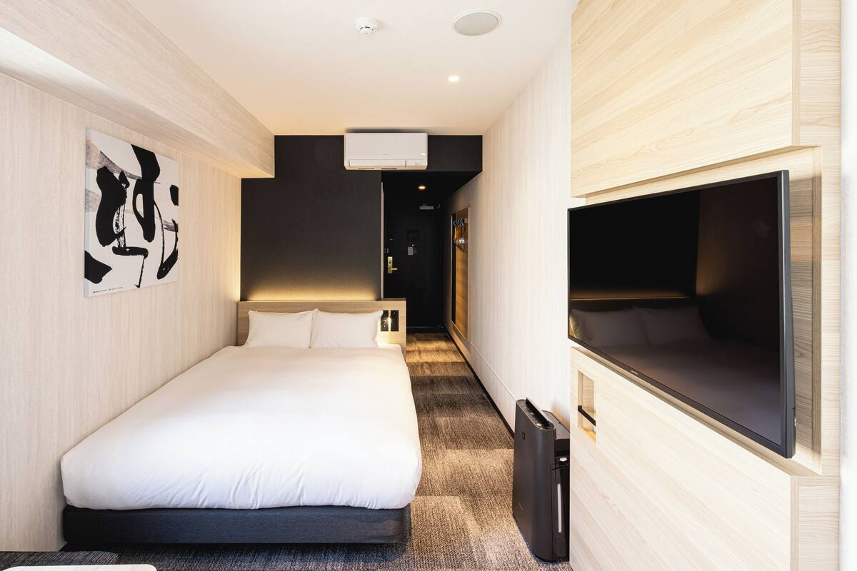Una habitación de hotel moderna con una cama grande, un televisor de pantalla plana y un diseño minimalista.