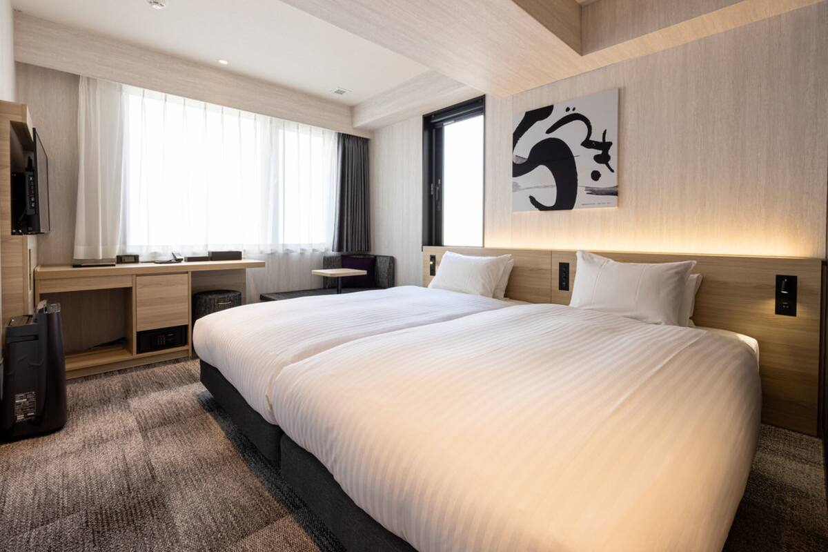 Una habitación de hotel moderna con una cama grande, un escritorio y una televisión.