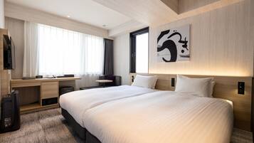 A modern hotel room with a large bed, a desk, and a television.