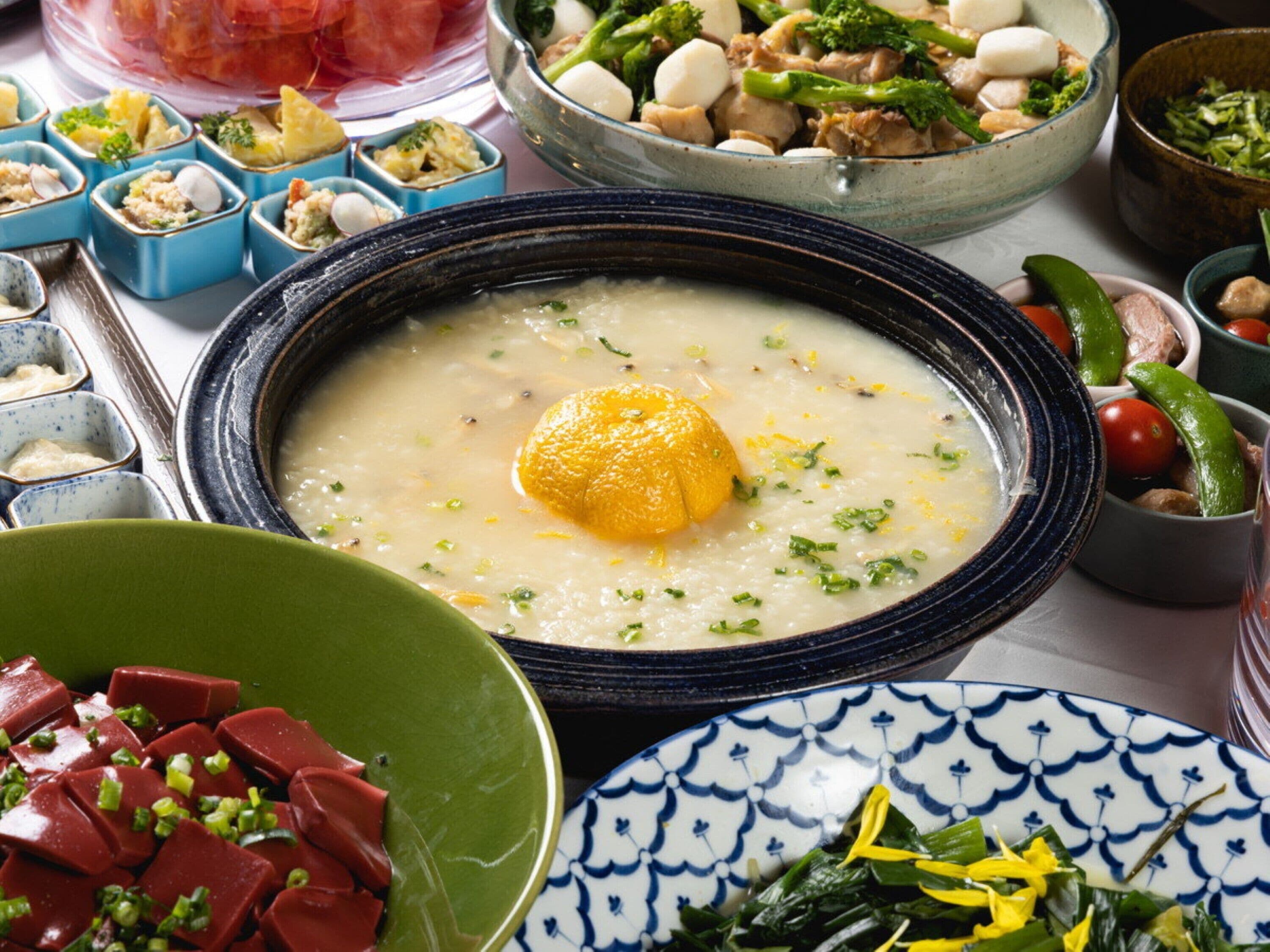 Variedad de platos, incluyendo un tazón de sopa con una rodaja de limón, un plato de carne en porciones y varios recipientes pequeños con distintos alimentos.