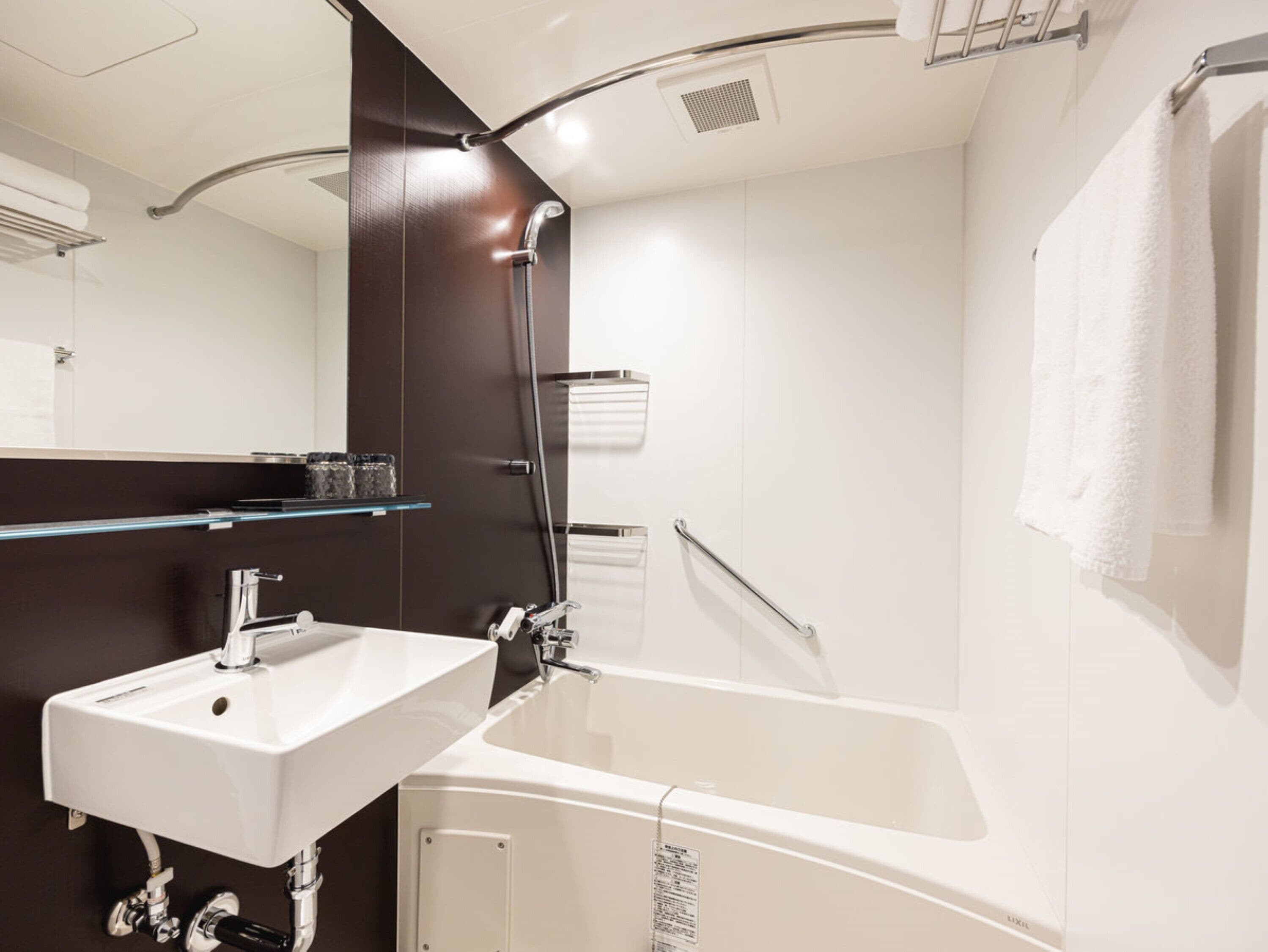 Une salle de bain moderne avec un lavabo blanc, une baignoire et un meuble-lavabo de couleur marron foncé.