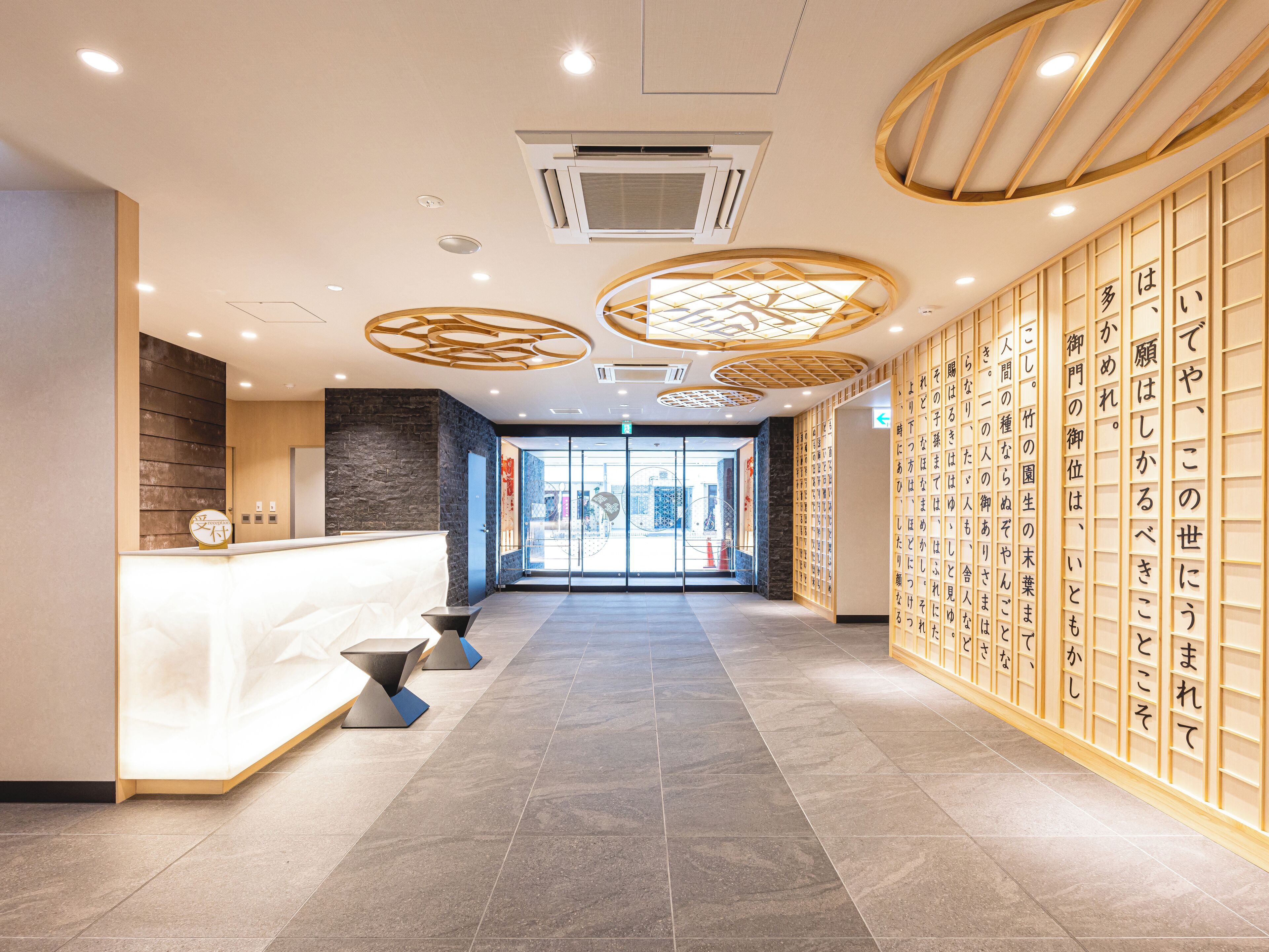 A modern reception area with a reception desk, a wall with calligraphy, and a tiled floor.