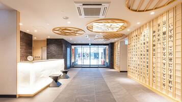 A modern reception area with a reception desk, a wall with calligraphy, and a tiled floor.
