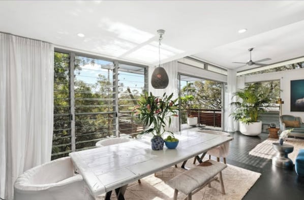 Enjoy meals in a spacious dining area with a large table for two, surrounded by lush views and potted plants.