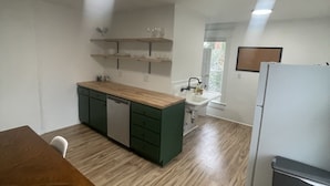 Una cocina compacta con una mesa de madera, un lavamanos y un refrigerador.