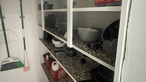 Una cocina con estantes blancos, una cesta roja y una caja de primeros auxilios.