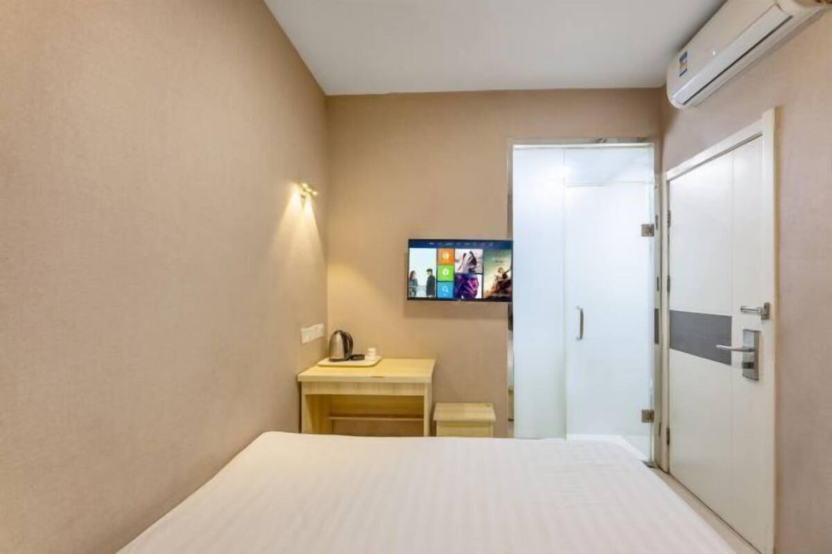 A hotel room with a bed, a desk, a television, and a wardrobe.