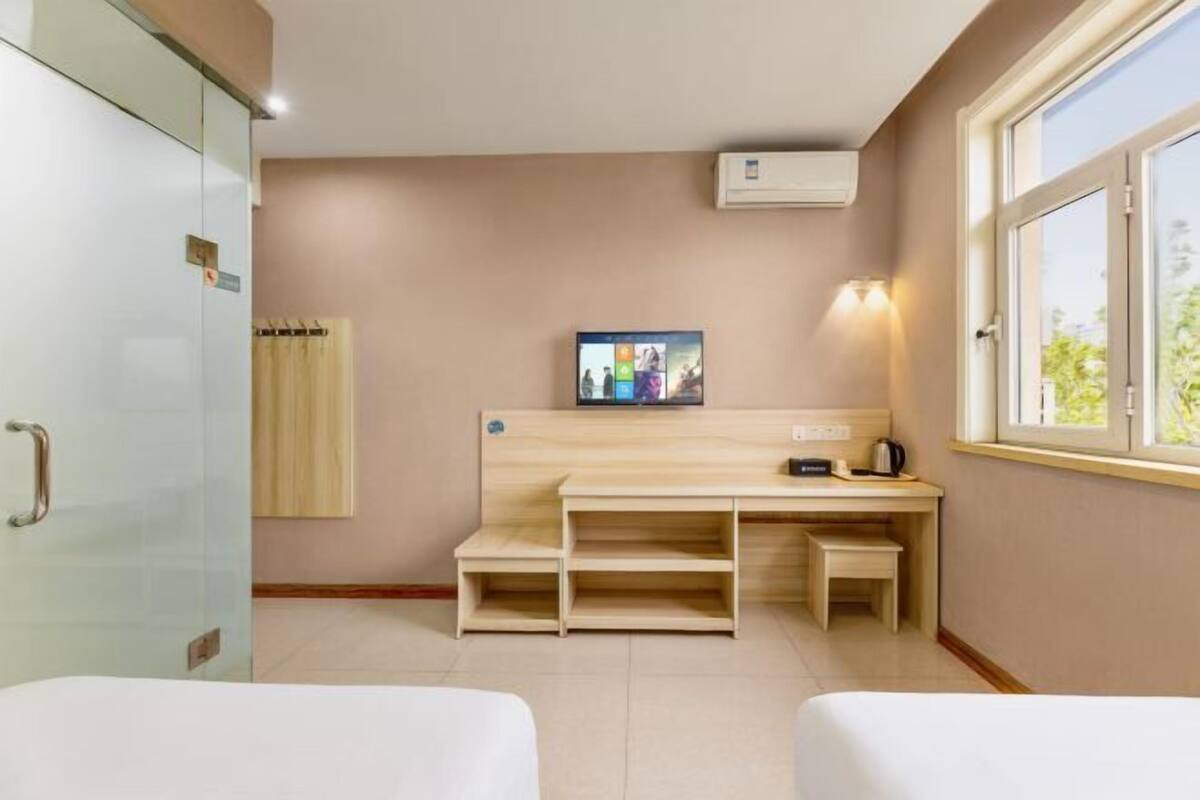 A hotel room with a bed, a desk with a computer, a window, and a wardrobe.