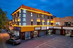 Um hotel com estilo arquitetônico tradicional, com telhado de azulejos e letreiros iluminados.