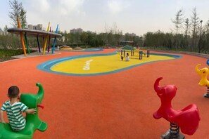 A playground with colorful play equipment and a yellow and orange play surface. - More Joy Express Hotel (Dacheng)