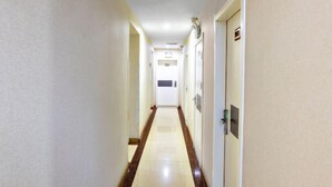 A long, narrow hotel hallway with doors on both sides and a central walkway. - More Joy Express Hotel (Dacheng)