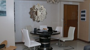 Zona pranzo moderna con tavolo rotondo, sedie bianche e uno specchio decorativo al muro.