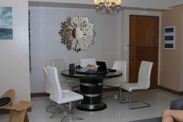 A modern dining area with a round table, white chairs, and a decorative mirror on the wall. - Very quiet place close to shops, restaurants, casino and international airports (Pasay)