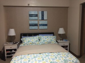 A hotel room with a bed, two bedside tables, and a wall-mounted artwork. - Very quiet place close to shops, restaurants, casino and international airports (Pasay)