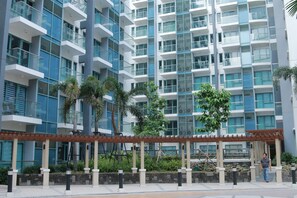 A modern multi-story building with balconies, a covered walkway, and greenery. - Very quiet place close to shops, restaurants,  casino and international airports (Pasay)
