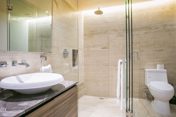 Une salle de bain moderne avec une douche à parois de verre, un lavabo blanc et des toilettes.