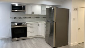Une cuisine moderne avec des meubles blancs, un réfrigérateur en acier inoxydable, un four à micro-ondes et une cuisinière.