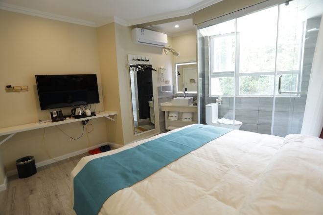 A hotel room with a bed, a TV, a bathroom with a mirror, and a window.