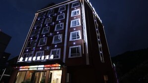 Un edificio de hotel de varios pisos con ventanas iluminadas y un letrero que indica que es un hotel.