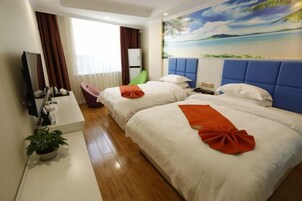 Habitación de hotel con dos camas, un ventanal con cortinas, un cuadro de playa, una planta en maceta y un escritorio con espejo y artículos de aseo.