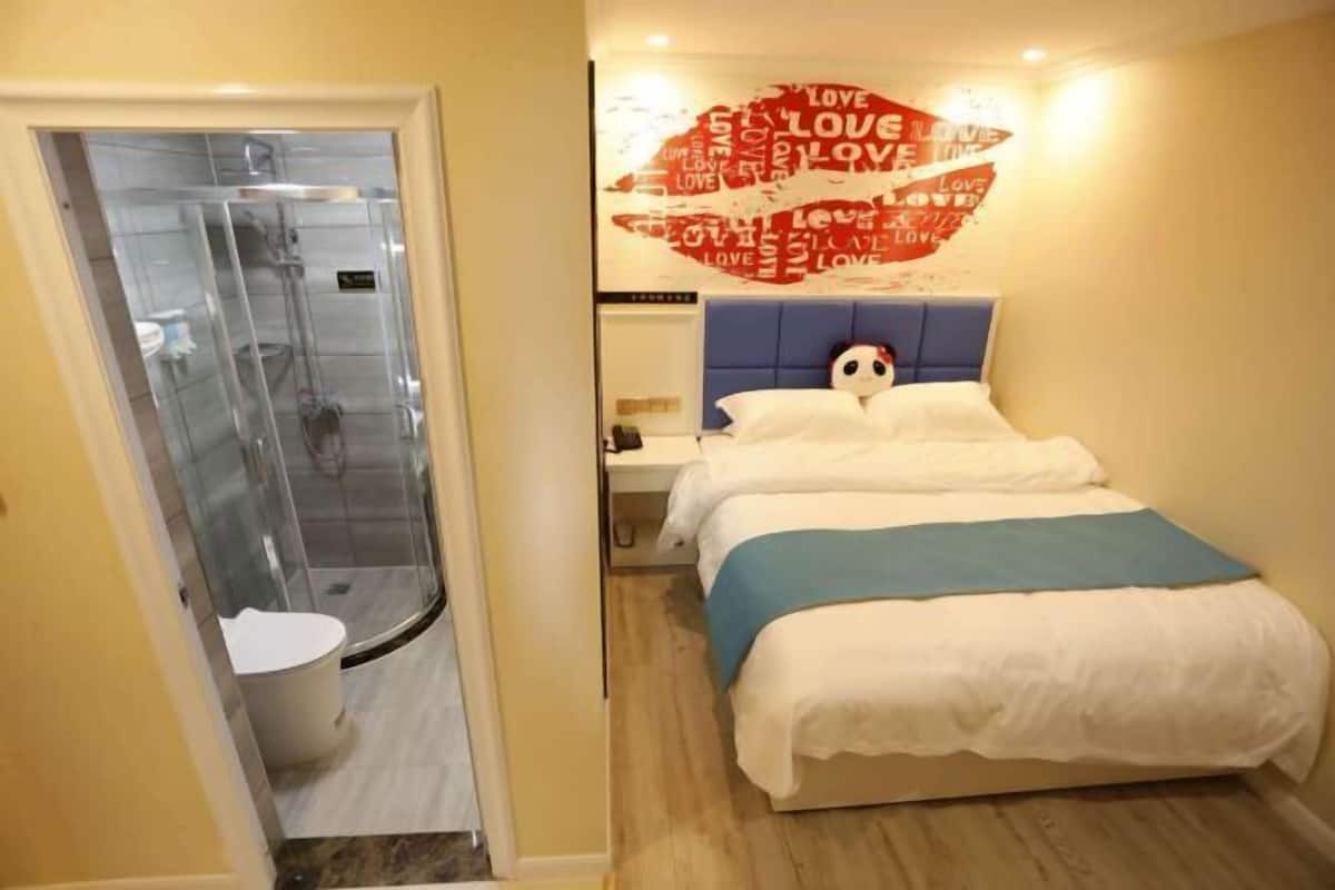 Ein Hotelzimmer mit Bett, Dusche und Wand mit Herzdesign.