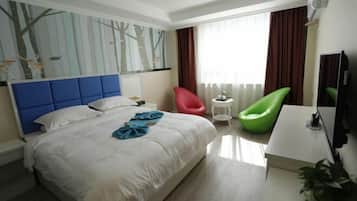 A hotel room with a large bed, a desk, a chair, a TV, and a window with curtains.