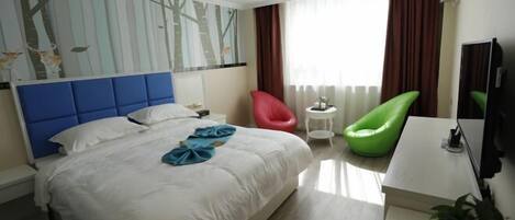 Ein Hotelzimmer mit einem großen Bett, einem Schreibtisch, einem Sessel, einem Fernseher und einem Fenster mit Vorhängen.
