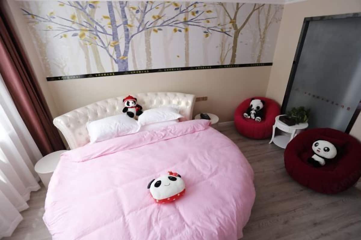 Ein Schlafzimmer mit einem Bett, einer Wand mit Baum-Wandgemälde und zwei roten Sitzsäcken.