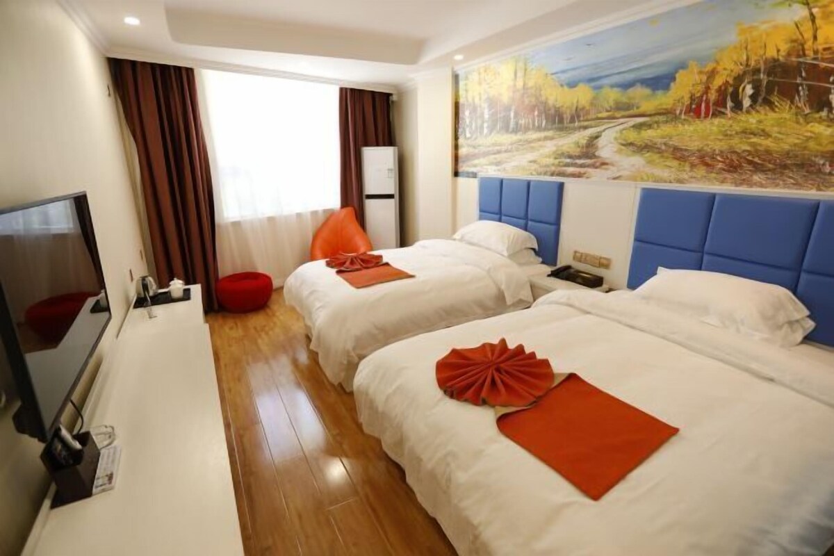 A hotel room with two beds, a flat-screen TV, a red chair, and a painting on the wall.