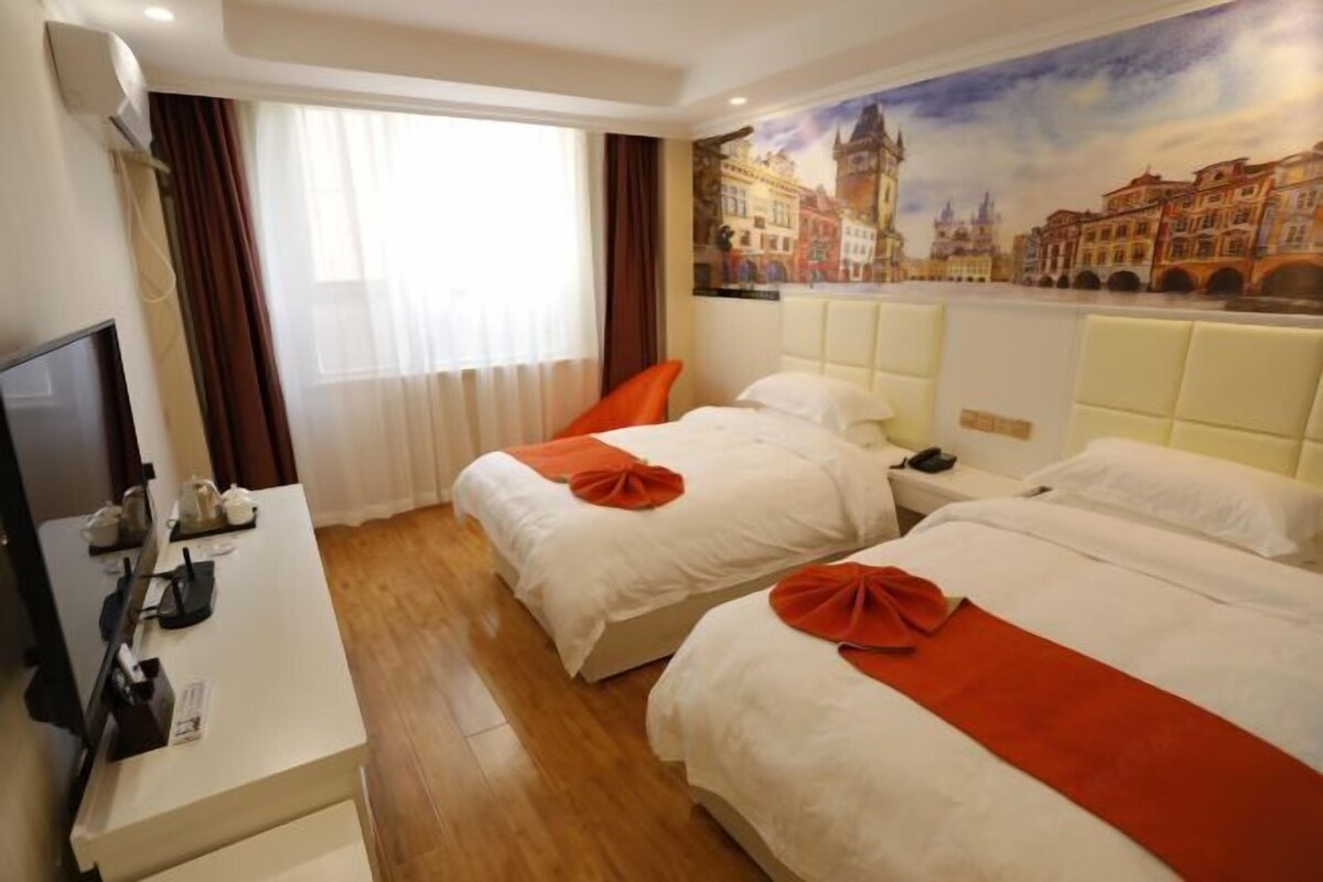 A hotel room with two beds, a TV, and a painting of a cityscape on the wall.