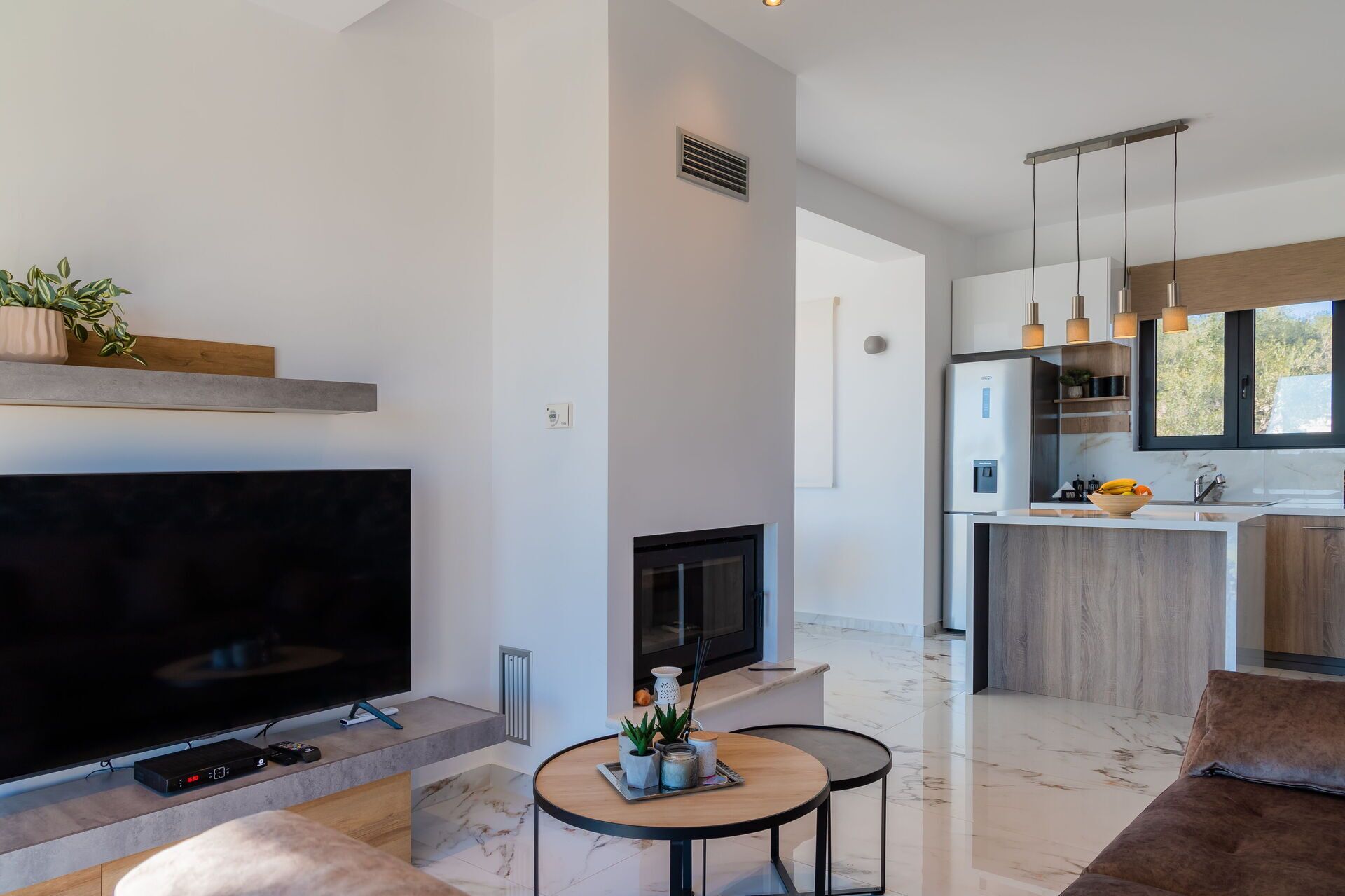 Een moderne woonkamer met een flatscreen-tv, een open haard en een eethoek met een ronde tafel.