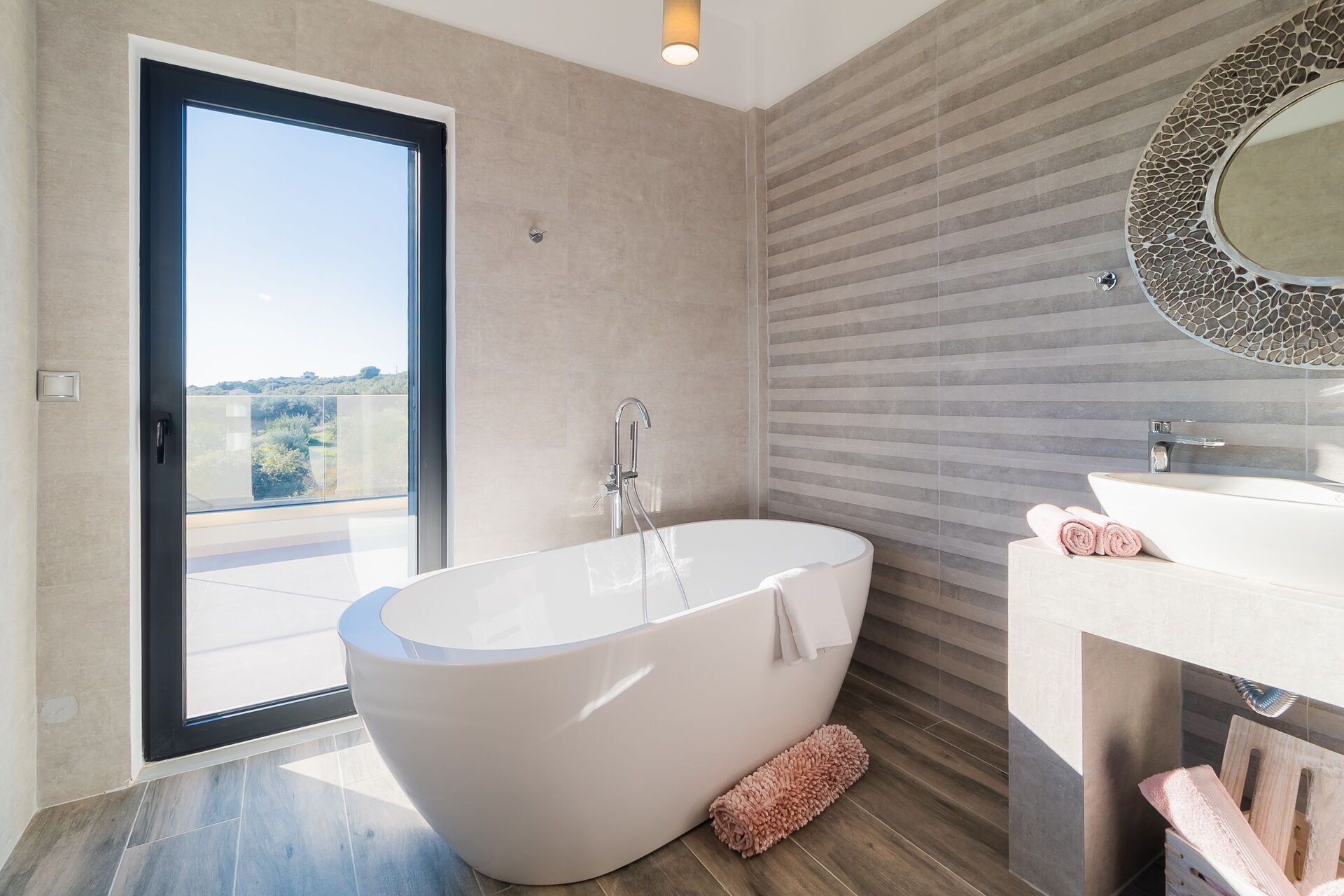 A modern bathroom with a freestanding bathtub, a sink, and a large mirror.