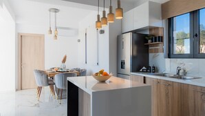 Una cocina moderna con una isla central, electrodomésticos de acero inoxidable e iluminación colgante.