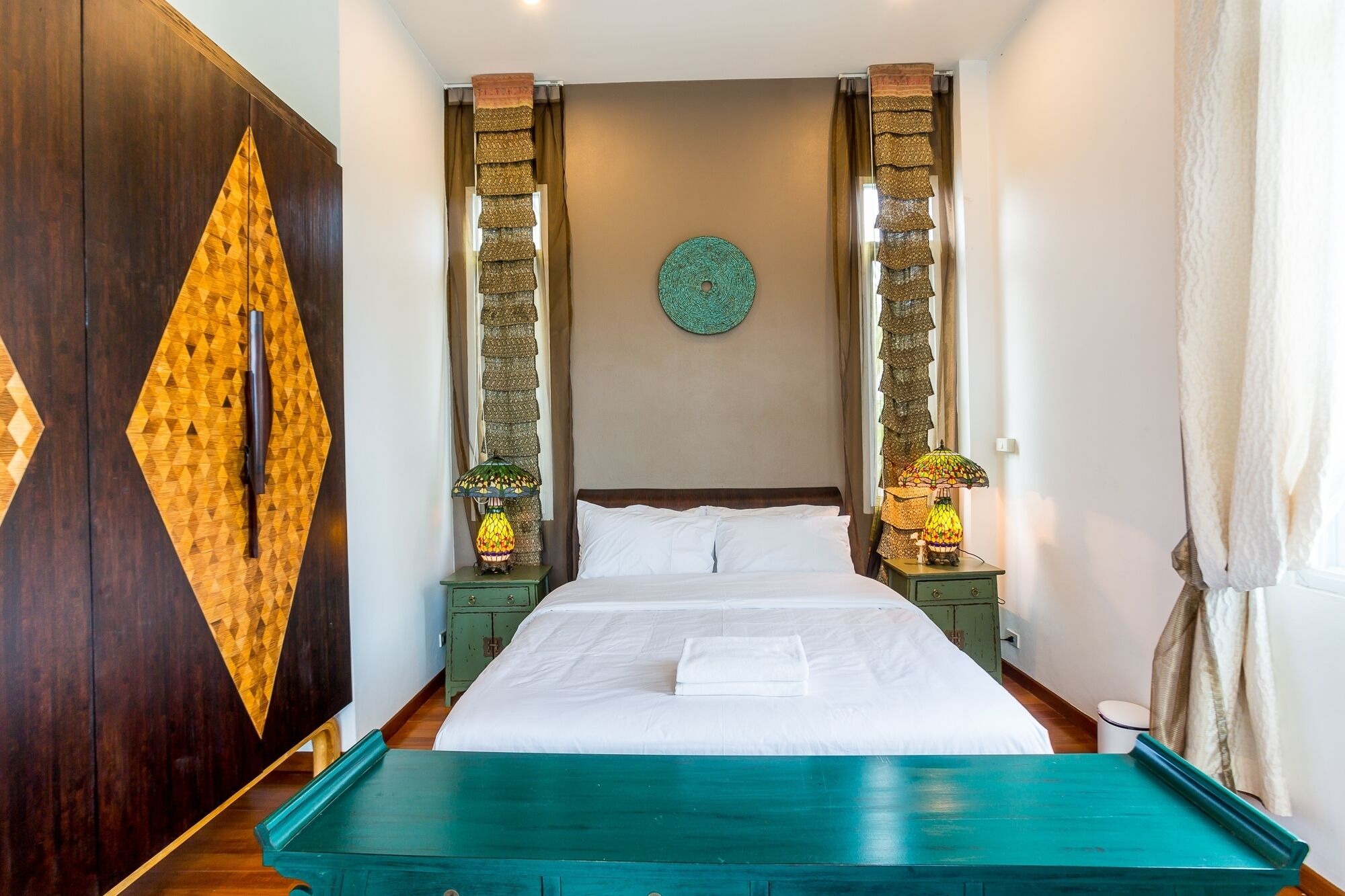 Une chambre d’hôtel avec un grand lit, deux tables de chevet avec des lampes, une armoire en bois et une décoration murale.