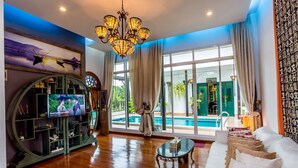 Ein geräumiges Wohnzimmer mit großem Fenster, Pool und Fernseher auf einem Holzkasten.