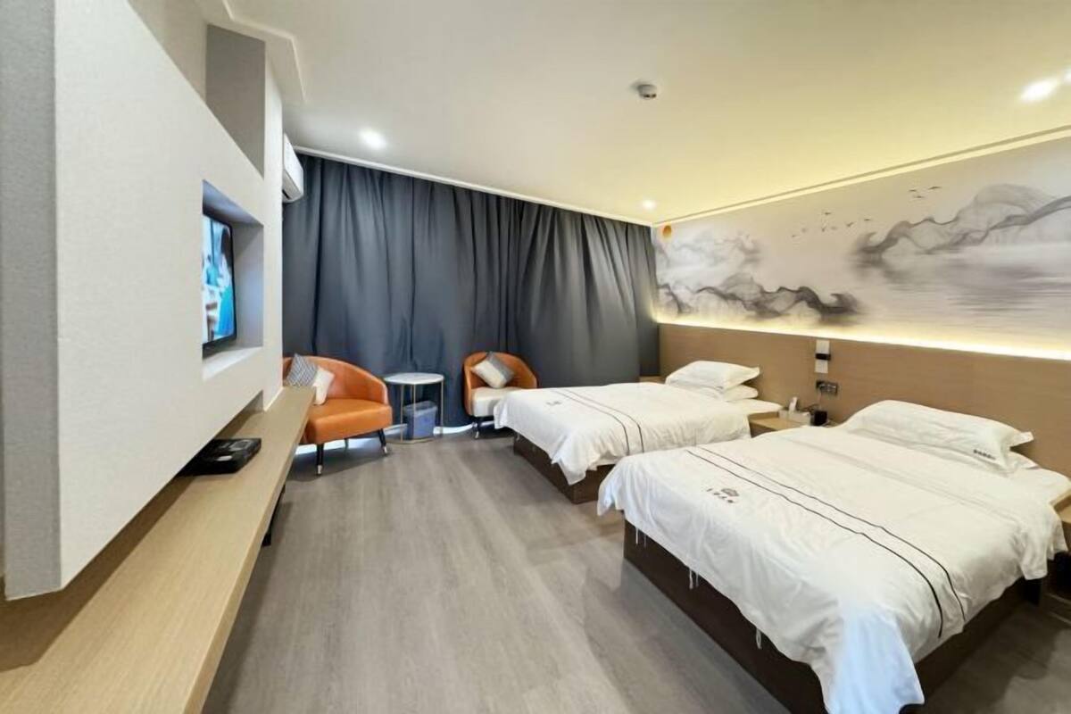 A hotel room with two beds, a TV, a desk, and a chair.