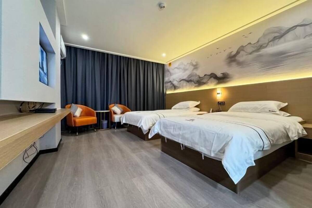 A hotel room with two beds, a desk, and a chair.
