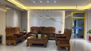 A modern lobby with wooden furniture, a marble wall, and a glass door. - Xinhuangdu Hotel, Xupu (Lipu)