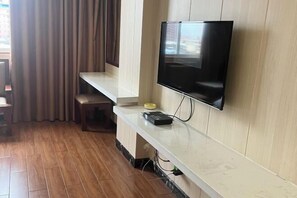 A modern hotel room with a flat-screen TV mounted on the wall, a wooden floor, a built-in bench, and a window with curtains. - Xinhuangdu Hotel, Xupu (Lipu)