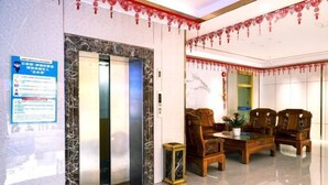 A lobby with an elevator, wooden furniture, and a marble wall. - Xinhuangdu Hotel, Xupu (Lipu)