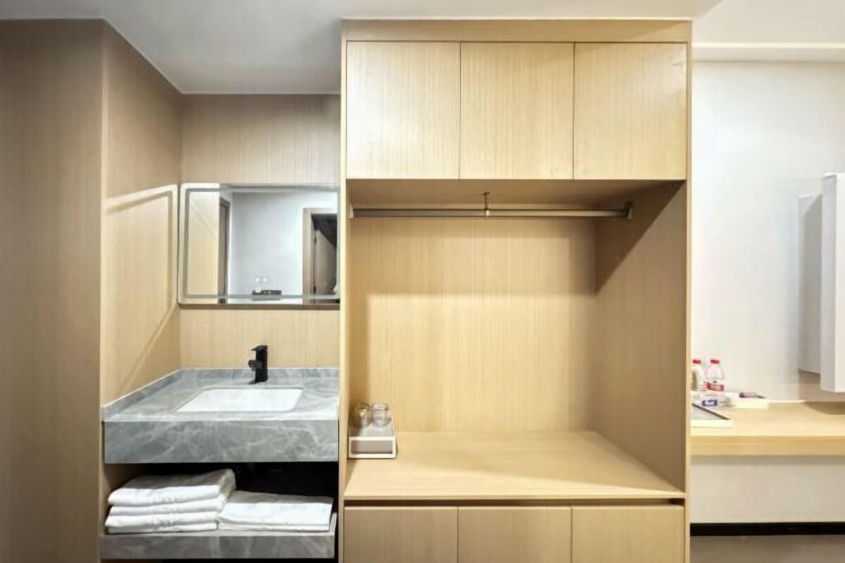 A modern bathroom with a marble sink, a mirror, and wooden cabinets.
