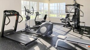 Une salle de sport équipée de tapis de course, de vélos elliptiques et d’appareils de musculation.