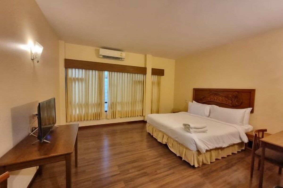 A hotel room with a bed, a desk, a chair, and a window with curtains.