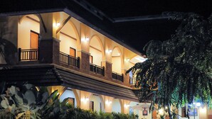 Hotel amb un balcó al segon pis, diverses làmpades i una zona de jardí ben cuidada.
